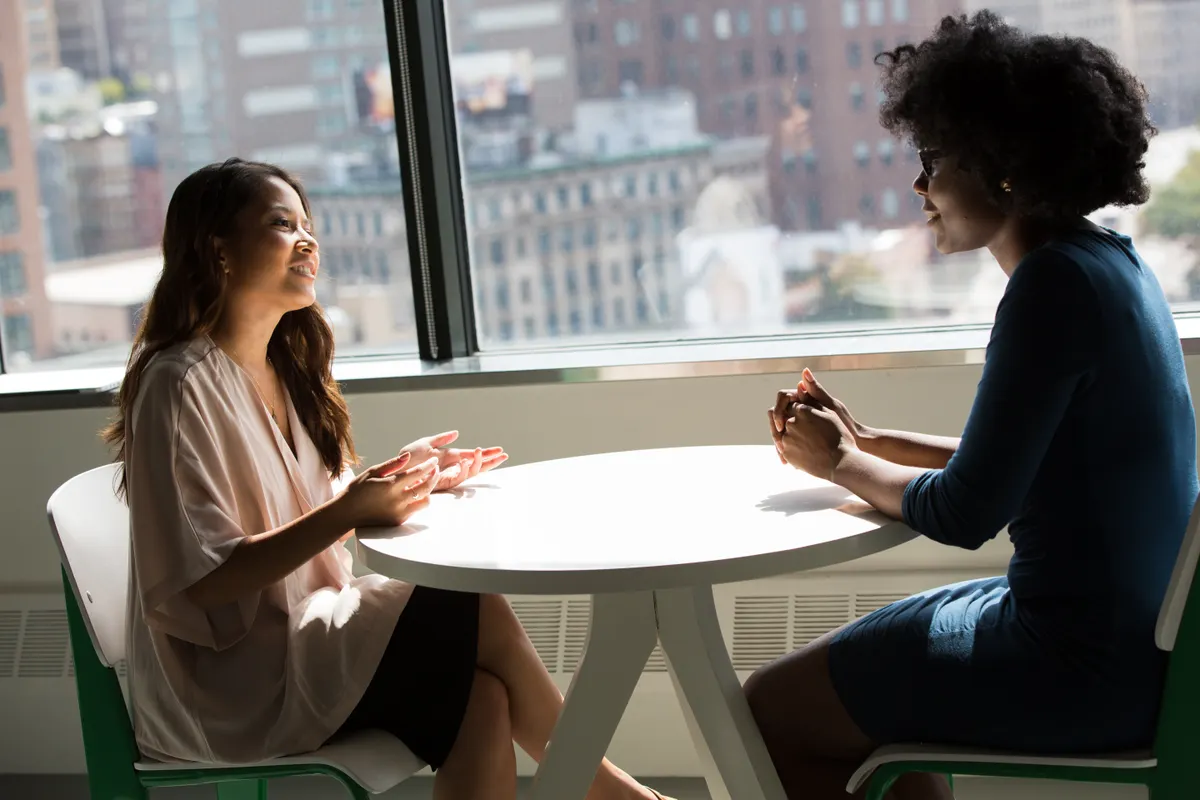 Two women in conversation at a table; illustrative stock photograph.